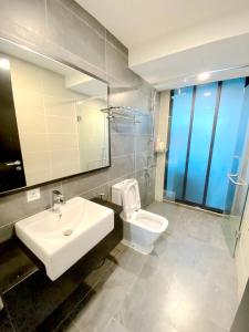 a bathroom with a sink and a toilet and a mirror at Almas Suites Puteri Harbour in Nusajaya