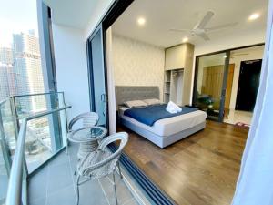 a bedroom with a bed and chairs and a balcony at Almas Suites Puteri Harbour in Nusajaya
