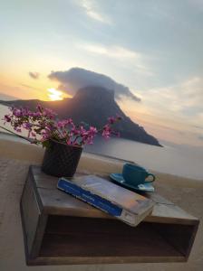 a table with a book and a cup of coffee and flowers at AFRODITI Hotel Studios in Masouri