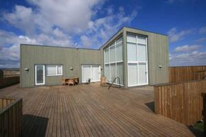 a building with a wooden deck with a bench on it at Golden Circle Luxury Villa in Selfoss