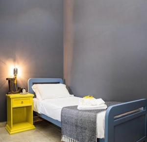 ein kleines Schlafzimmer mit einem Bett und einem gelben Nachttisch in der Unterkunft Lako Hostel in Capodimonte