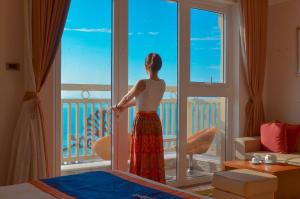 a woman looking out the window of a hotel room at BlueSun Danang Beach Hotel in Da Nang