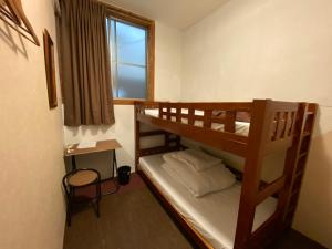 Łóżko piętrowe w pokoju z biurkiem i oknem w obiekcie Nomad Hostel East w Tokio