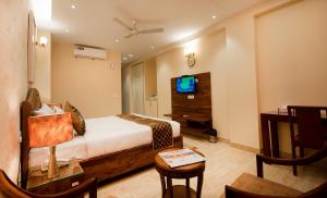 ein Hotelzimmer mit einem Bett und einem TV in der Unterkunft Imperial Apartments Huda City in Gurgaon