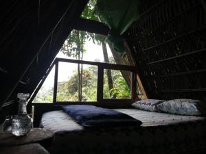 Cama en habitación con ventana en Jungle Roots, en Tena