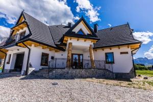 a white house with a black roof at Apartament Parzenica in Poronin