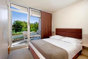 a bedroom with a large bed and a balcony at Hotel Mediteran Plava Laguna in Poreč