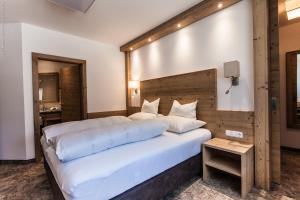 1 dormitorio con 1 cama blanca grande y cabecero de madera en Schönblick Appartements, en Tux