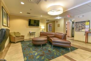 une salle d'attente avec un canapé en cuir et une télévision dans l'établissement Candlewood Suites Medford, an IHG Hotel, à Medford