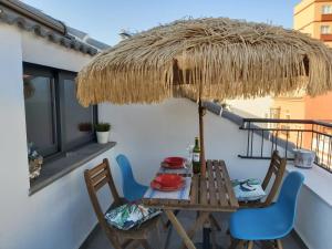 uma mesa e cadeiras numa varanda com um guarda-sol de palha em Bnbook Medea Apartments em Fuengirola