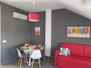Bnbook Medea Apartments في فوينخيرولا: غرفة طعام مع أريكة حمراء وطاولة