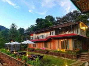 a house with tables and umbrellas in front of it at Bann Suan Maya in Mae Rim