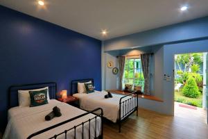 a bedroom with two beds and a blue wall at Little Cottage in Chanthaburi