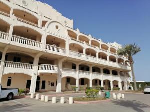 a large white building with a palm tree in front of it at Durrah Beach Apartment in Durat Alarous