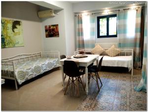 a room with two beds and a table and chairs at Amelie Apartment in Preveza