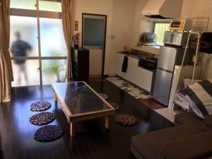 ein Wohnzimmer mit einem Tisch und einer Küche in der Unterkunft STAY IN ALOHA in Tokashiki