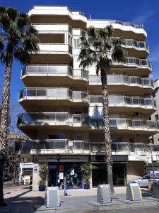 un grand bâtiment avec des palmiers devant dans l'établissement SCALA Apartaments, à Salou