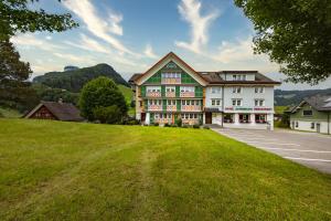 un gran edificio con un césped verde delante de él en Hotel Alpenblick en Weissbad