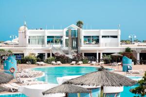 un complexe doté d'une piscine avec des chaises longues et des parasols dans l'établissement HL Club Playa Blanca, à Playa Blanca