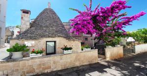 a building with purple flowers and a tree at Trulli Antica Fonte in Alberobello