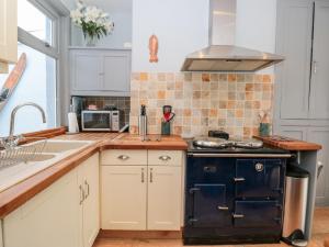 a kitchen with white cabinets and a blue stove at Anchor Cottage in Salcombe