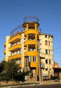 a yellow apartment building with a balcony at Семеен хотел Бостън in Ravda