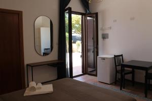 una camera con letto, specchio e tavolo di B&B Nettuno San Leone a San Leone