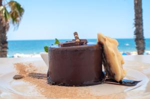 a chocolate cake on a plate on the beach at Hotel Agaró in Chipiona