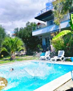 a swimming pool with two chairs and a house at Apartments Bozana Bibinje in Bibinje