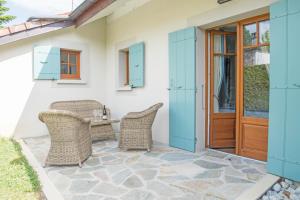 a patio with wicker chairs and a wooden door at Villa Cécile in Yvoire