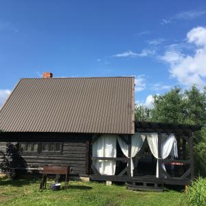 une cabane en rondins avec des rideaux blancs et un toit dans l'établissement Stay at hosts, à Rēzekne