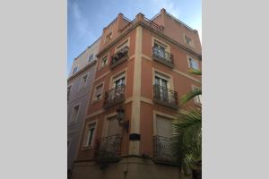 a tall orange building with balconies and a palm tree at céntrico apartamento La Llum 1A in Alicante