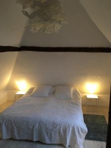 um quarto com uma cama branca e 2 candeeiros em La Chevalerie em Pont-lʼÉvêque