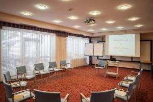 une salle de conférence avec des chaises et un écran blanc dans l'établissement Hotel Wende, à Neusiedl am See