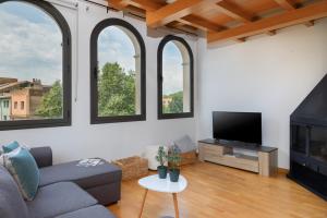 a living room with a couch and a tv and windows at Flateli Sant Fèlix in Girona