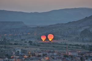 dos globos de aire caliente están volando sobre una ciudad en Cappadocia Cave Lodge, en Göreme