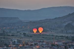 two hot air balloons are flying over a city at Cappadocia Cave Lodge in Goreme