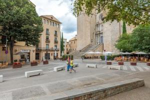two people walking down a city street with benches at Flateli Sant Fèlix in Girona