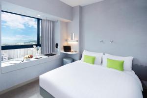 a bedroom with a large white bed and a window at Hotel Ease Mong Kok in Hong Kong