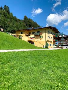 a yellow building on top of a grassy hill at Appartements Samerhof - TOP 1 in Kaltenbach
