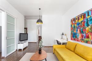 a living room with a yellow couch and a painting at New Quiet Cozy City Center apartment in Vilnius