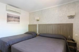 a bedroom with two beds and a picture on the wall at Hotel Les Palmiers En Camargue in Saintes-Maries-de-la-Mer