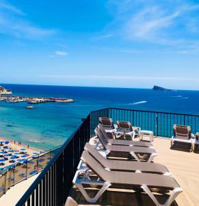 a group of lounge chairs on a balcony overlooking the ocean at Hotel Marconi in Benidorm