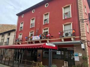 a red building with a red umbrella in front of it at Hostal Delgado in Benabarre