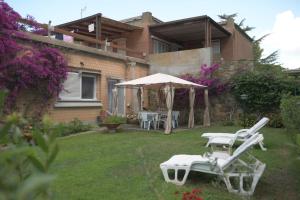 a house with two lawn chairs and an umbrella at Casa Gori in Punta Ala