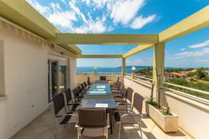 a patio with a long table and chairs on a balcony at Villa Ozzi with 9 bedrooms & private Pool in Makarska