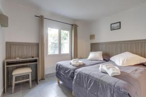 a bedroom with a bed and a desk and a window at Hotel Les Palmiers En Camargue in Saintes-Maries-de-la-Mer