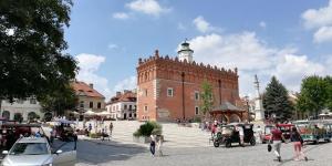 a group of people walking in front of a brick building at Apartament Przy Długosza in Sandomierz