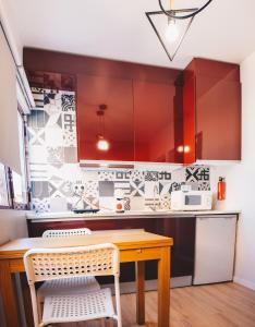 a kitchen with red cabinets and a wooden table at Apartamento Torreão in Póvoa de Varzim