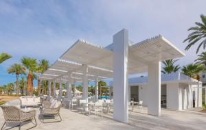 a pavilion with chairs and tables and palm trees at Occidental Sousse Marhaba in Sousse